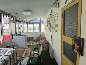 Una habitación con una mesa, sillas, un calefactor pequeño, una ventana con vistas y una puerta con mosquitero.