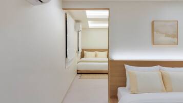 Una habitación de hotel con una cama, una mesita de noche, aire acondicionado de pared y un cuadro enmarcado.
