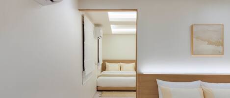 Una habitación de hotel con una cama, una mesita de noche, aire acondicionado de pared y un cuadro enmarcado.