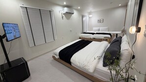 A modern bedroom with a bed, bedside table, wall-mounted air conditioning unit, and a television on a stand. - Stay Zam Hotel (Jung-gu)