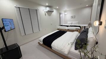 A modern bedroom with a bed, bedside table, wall-mounted air conditioning unit, and a television on a stand.