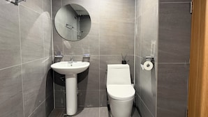 A modern bathroom with a white sink, toilet, and a round mirror on the wall. - Stay Zam Hotel (Jung-gu)