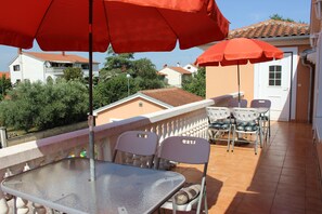 A terrace with a table and chairs, red umbrellas, and a view of surrounding buildings. - Ferienwohnung "Dorade" villa Riba in Pula ruhig trotzdem Zentrum und Meeresnähe (Pula)