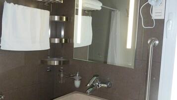 A modern bathroom with a built-in sink, a towel rack, a mirror, and a hand dryer.