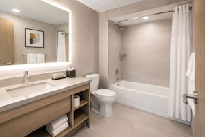 Ein modernes Badezimmer mit großem Spiegel, Waschbecken, Toilette und Badewanne.