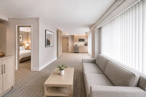 Ein Hotelzimmer mit Bett, einer Couch, einem Couchtisch und Blick auf einen Küchenbereich.