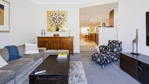 A modern living room with a sofa, a coffee table, and a patterned armchair. - Leederville Life - 2 Bedroom House (West Leederville)