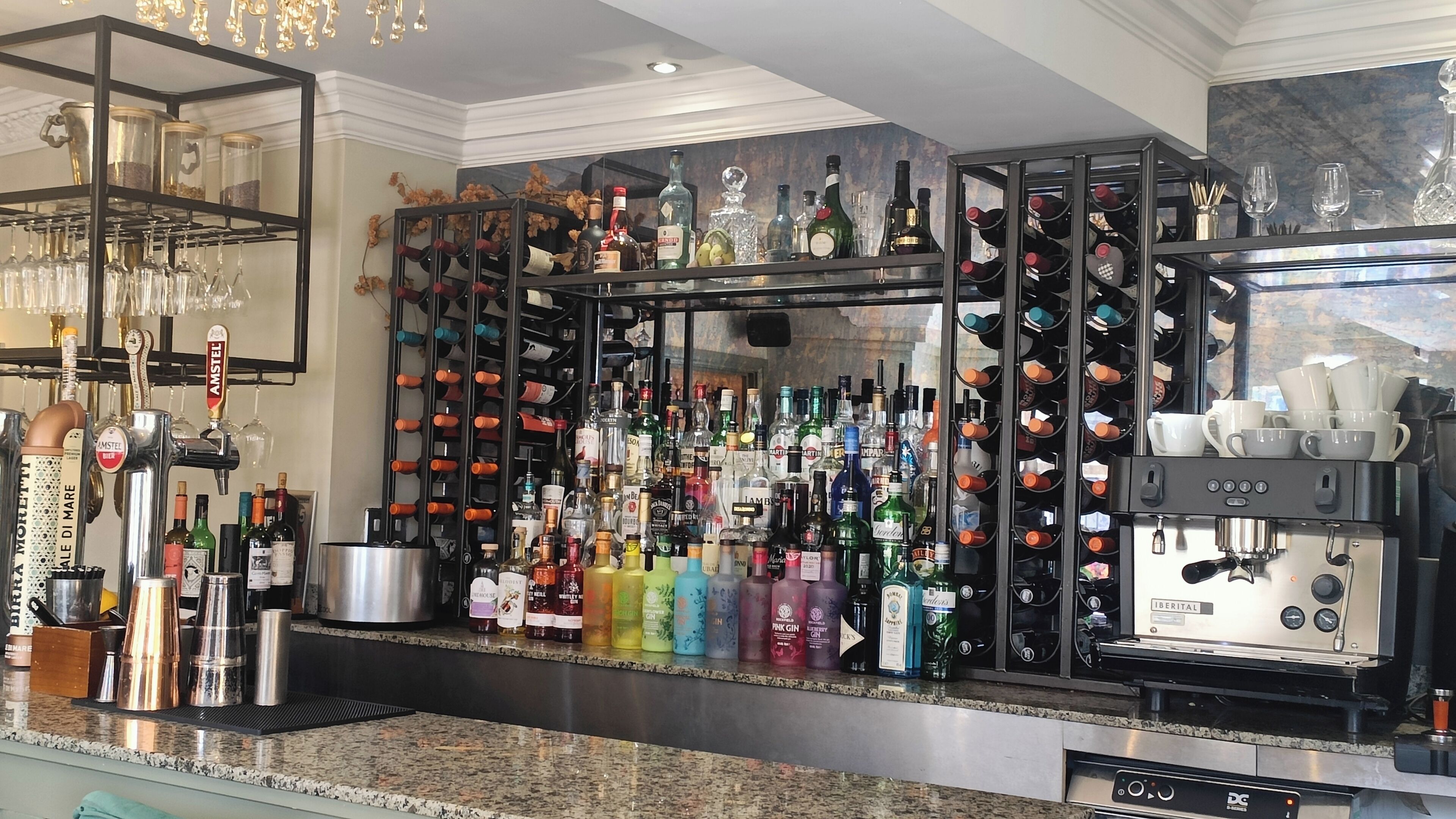 Zona de bar con una variedad de botellas de licor, una máquina de café y una estantería para vinos.