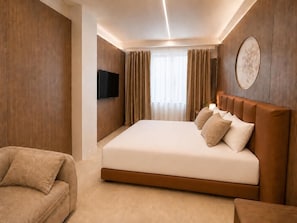 Une chambre d’hôtel avec un grand lit, un téléviseur à écran plat fixé au mur et un canapé.