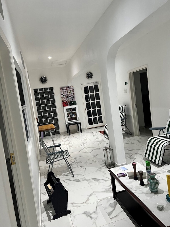 A spacious living area with a tiled floor, a dining table, and a seating arrangement including a chair and a sofa.