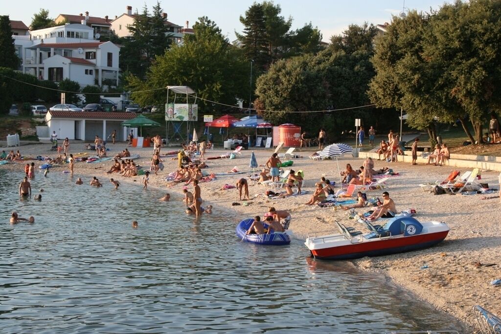 Une plage où l’on peut se baigner et bronzer, une tour de surveillance pour les sauveteurs, et une rangée de parasols.