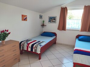 A bedroom with a bed, a dresser, a window with curtains, and wall art. - Schöne Ferienwohnung "Scampi" in ruhigem Stadtteil von Pula mit 2 Schlafzimmer (Pula)