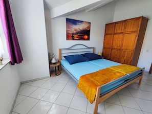 Ein Schlafzimmer mit einem Bett, einem Nachttisch, einer Lampe, einem Holzschrank und einem Bild an der Wand.