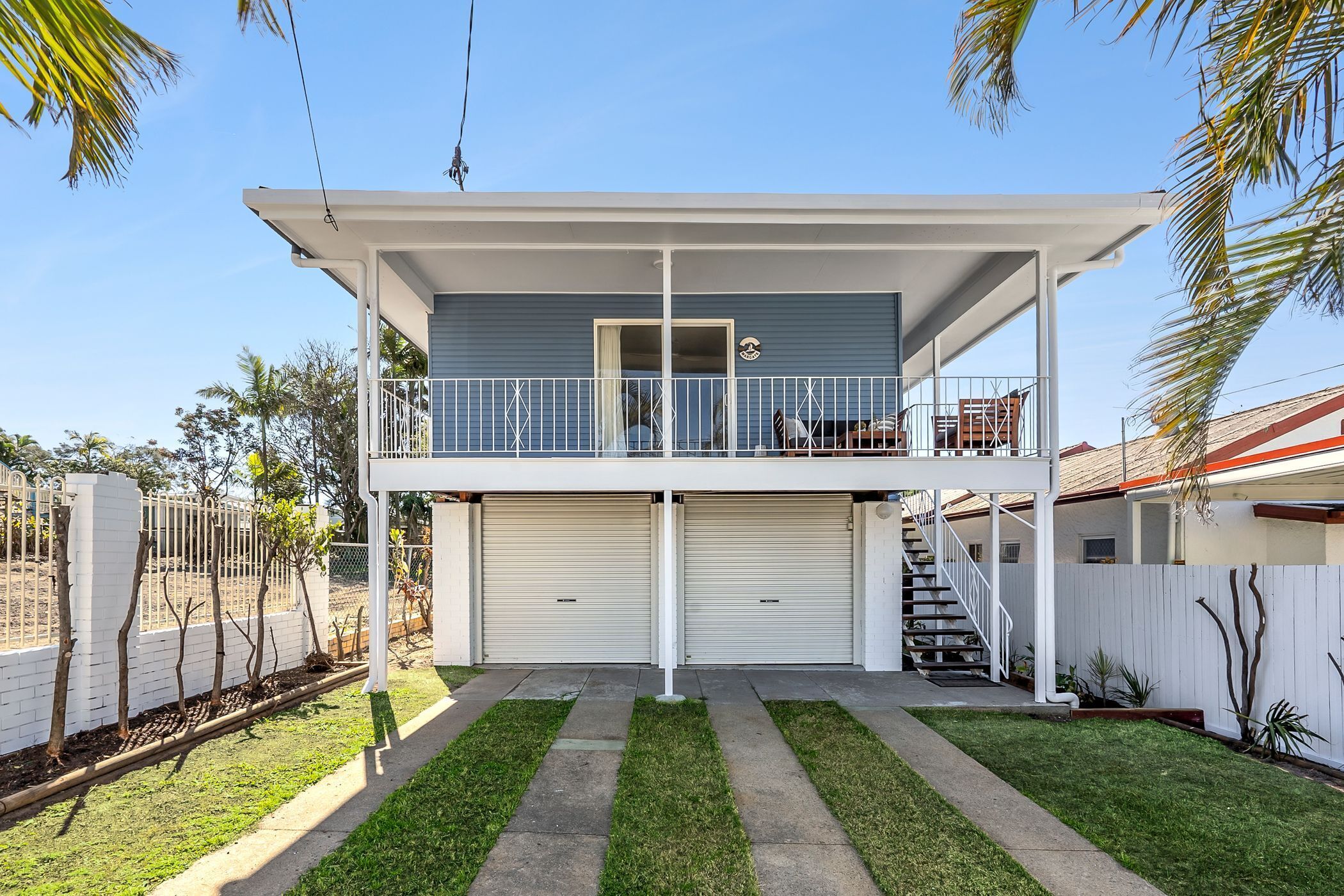 A two-story house with a balcony, a garage, and a well-maintained lawn.