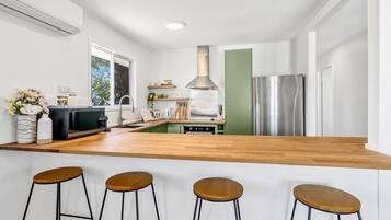 A modern kitchen with a wooden countertop, stainless steel appliances, and bar stools.