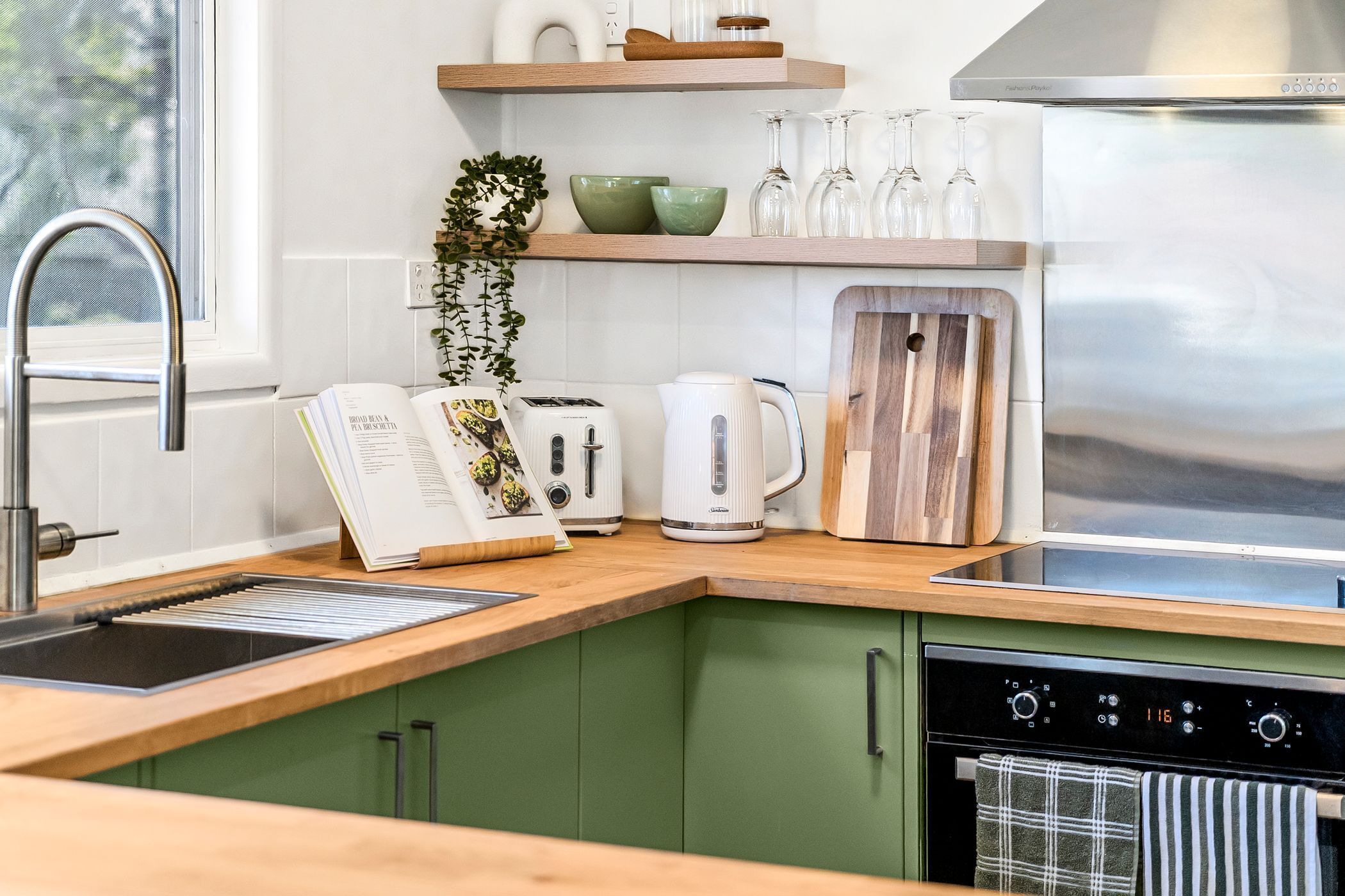 A modern kitchen with a wooden countertop, a built-in oven, a coffee maker, and a toaster.