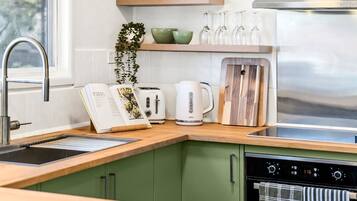 A modern kitchen with a wooden countertop, a built-in oven, a coffee maker, and a toaster.