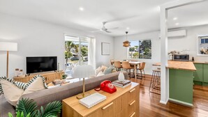Un espacio habitable moderno con sofá, televisor, comedor y cocina.