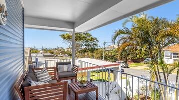 A balcony with wooden furniture, a view of the street, and a clear sky.