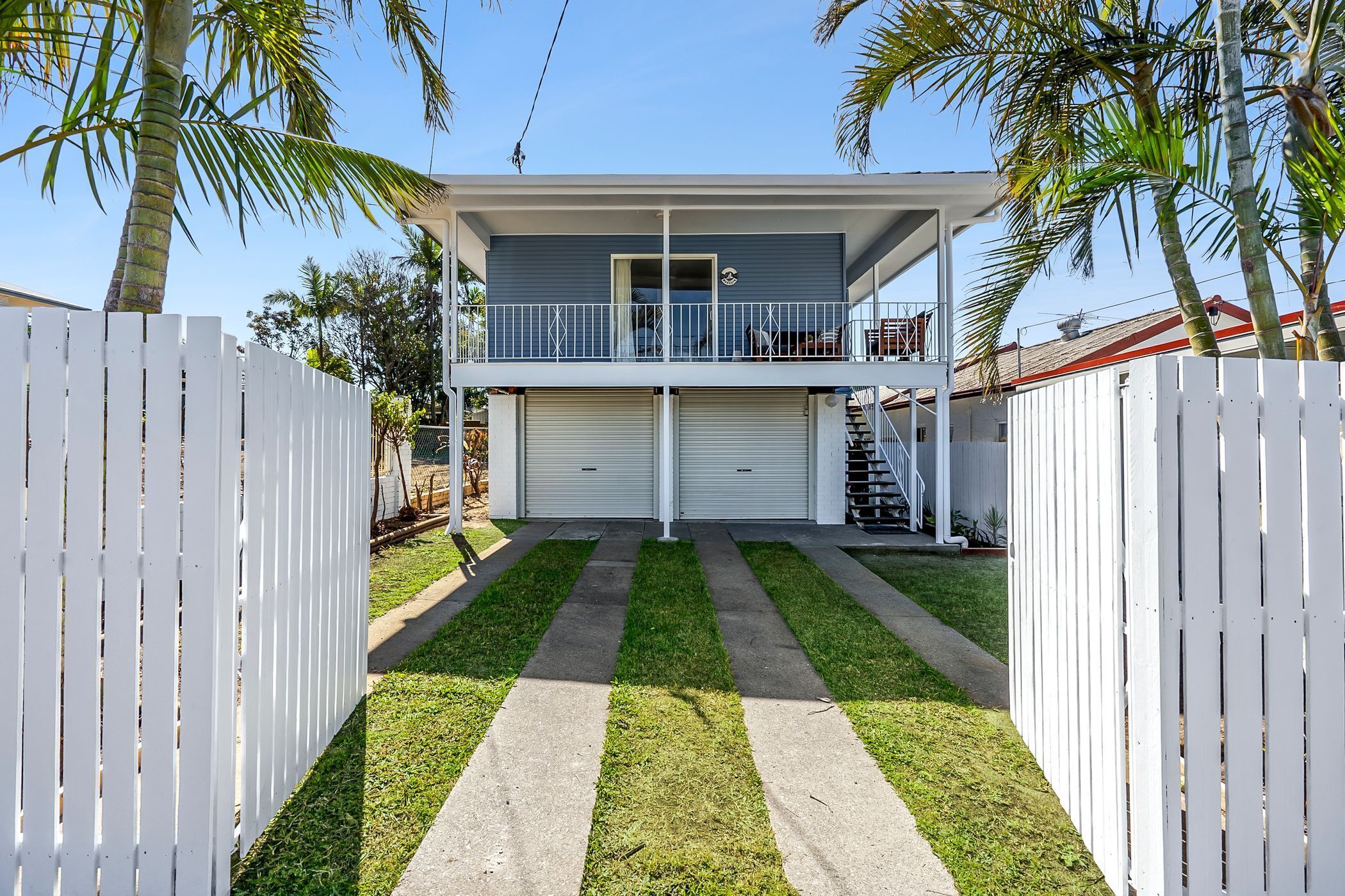 A two-story house with a balcony, a garage, and a well-maintained lawn.