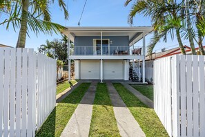 A two-story house with a balcony, a garage, and a well-maintained lawn.