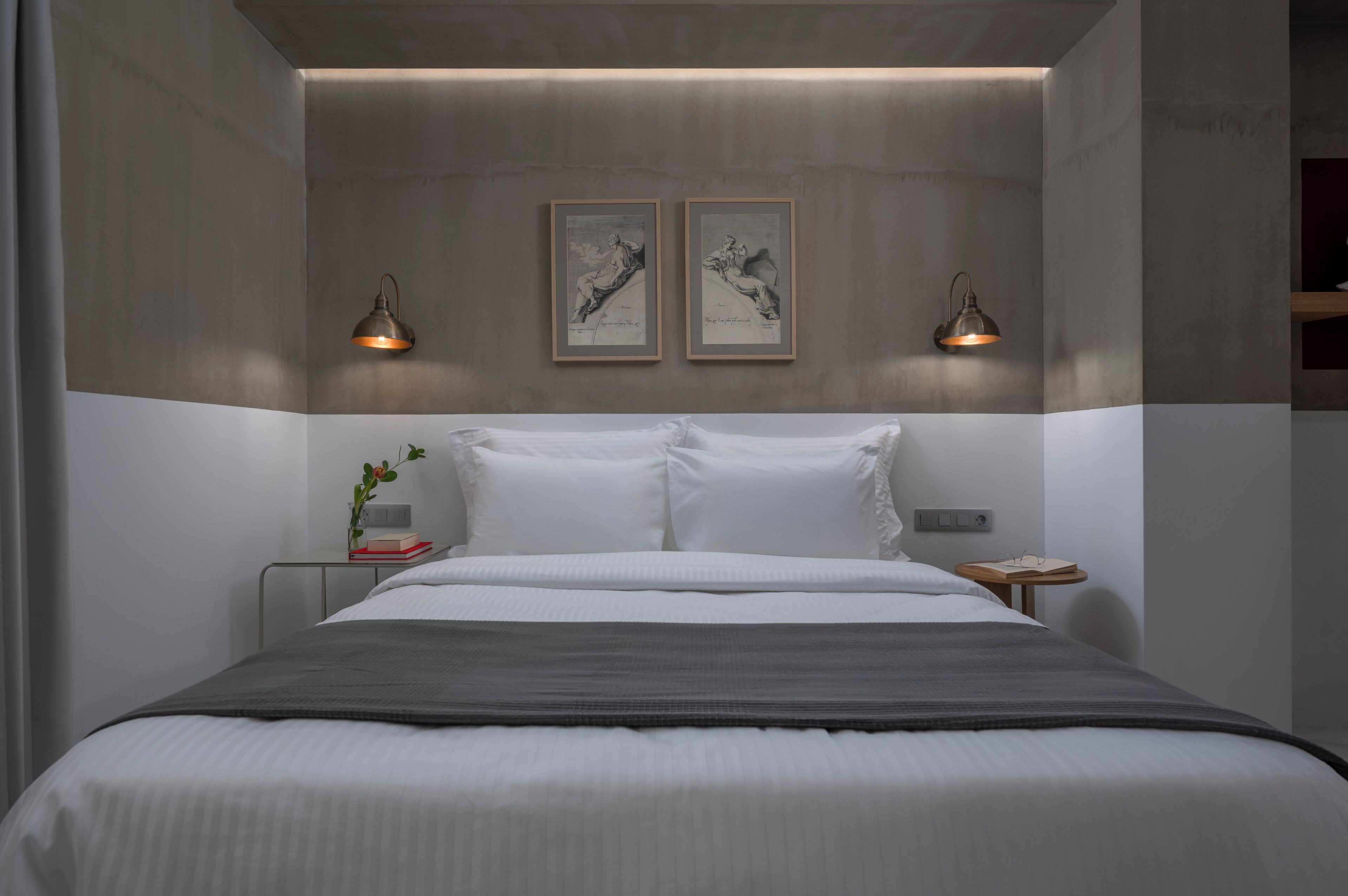 Een moderne slaapkamer met een groot bed, twee nachtkastjes en twee wandlampen.