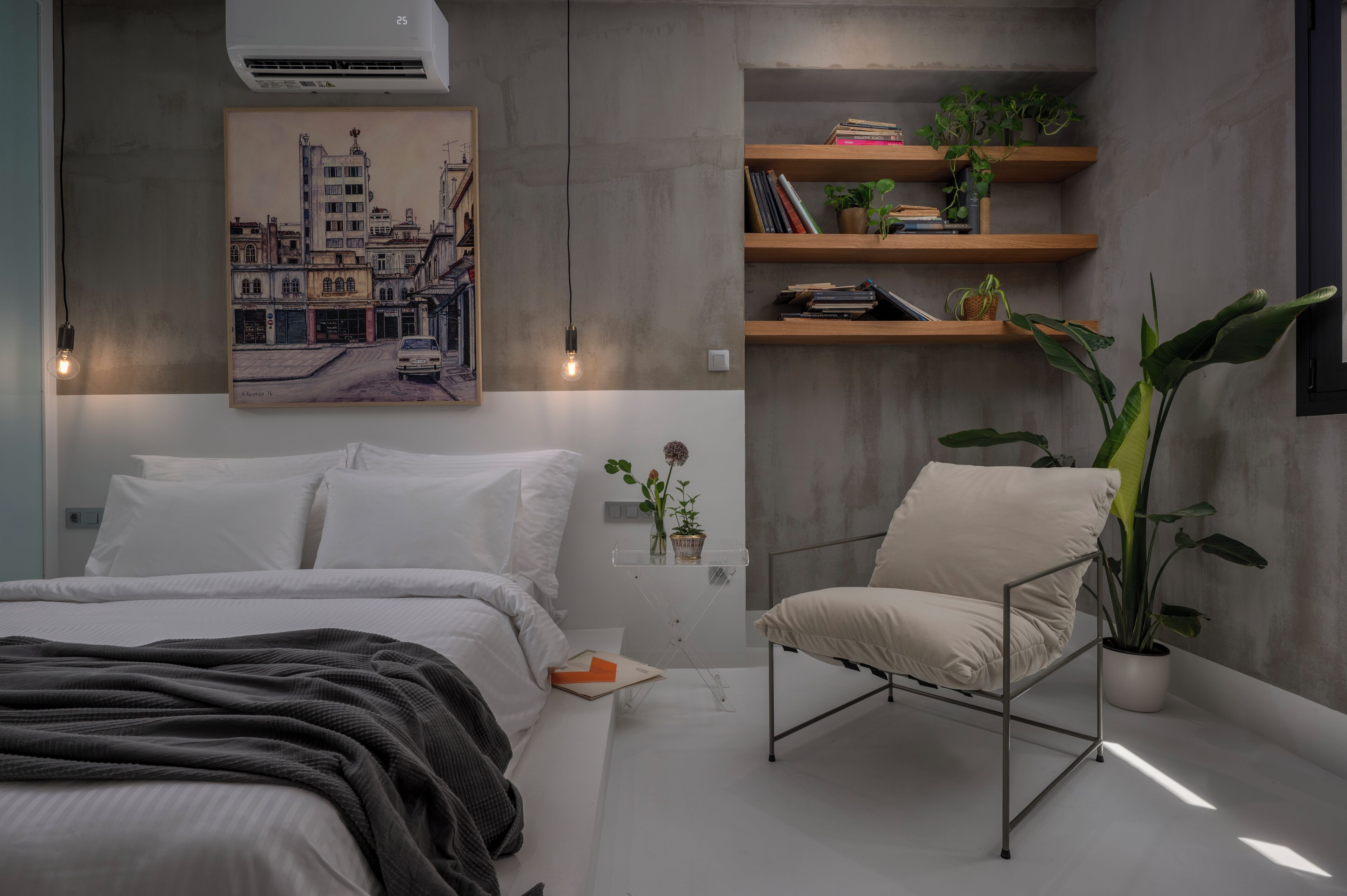 A bedroom with a bed, a chair, a shelf with books and plants, a painting on the wall, and an air conditioning unit.