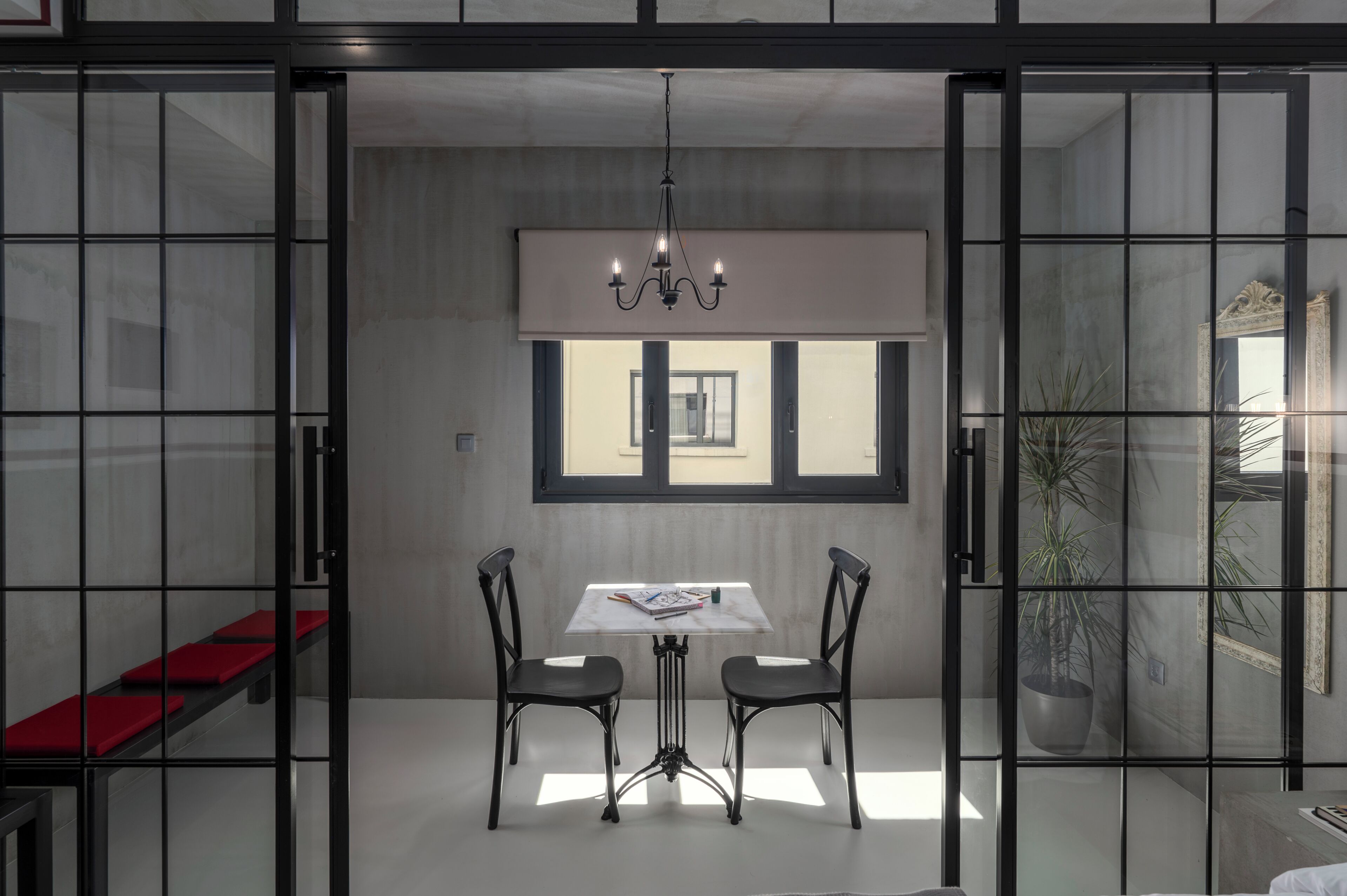 Et moderne spiseområde med et bord, stole, en lysekrone og udsigt gennem et vindue.