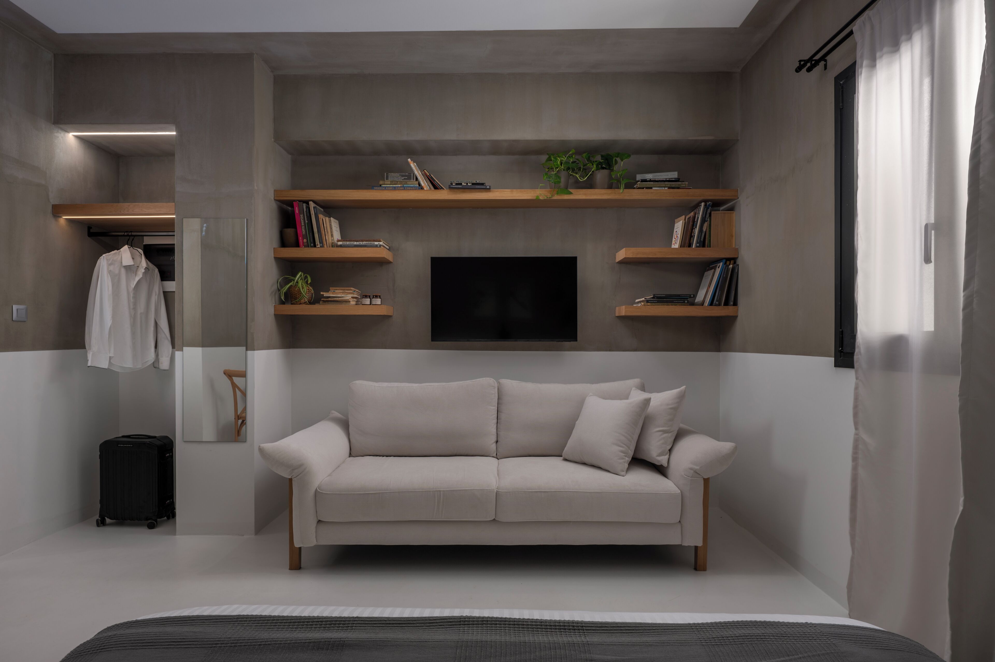 A modern living room with a sofa, a flat-screen TV, and built-in shelving with books and decorative items.