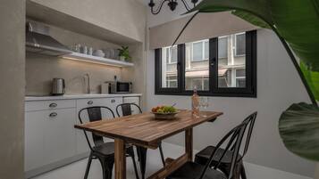 A compact kitchen with white cabinets, a wooden dining table, and a window with black shutters.