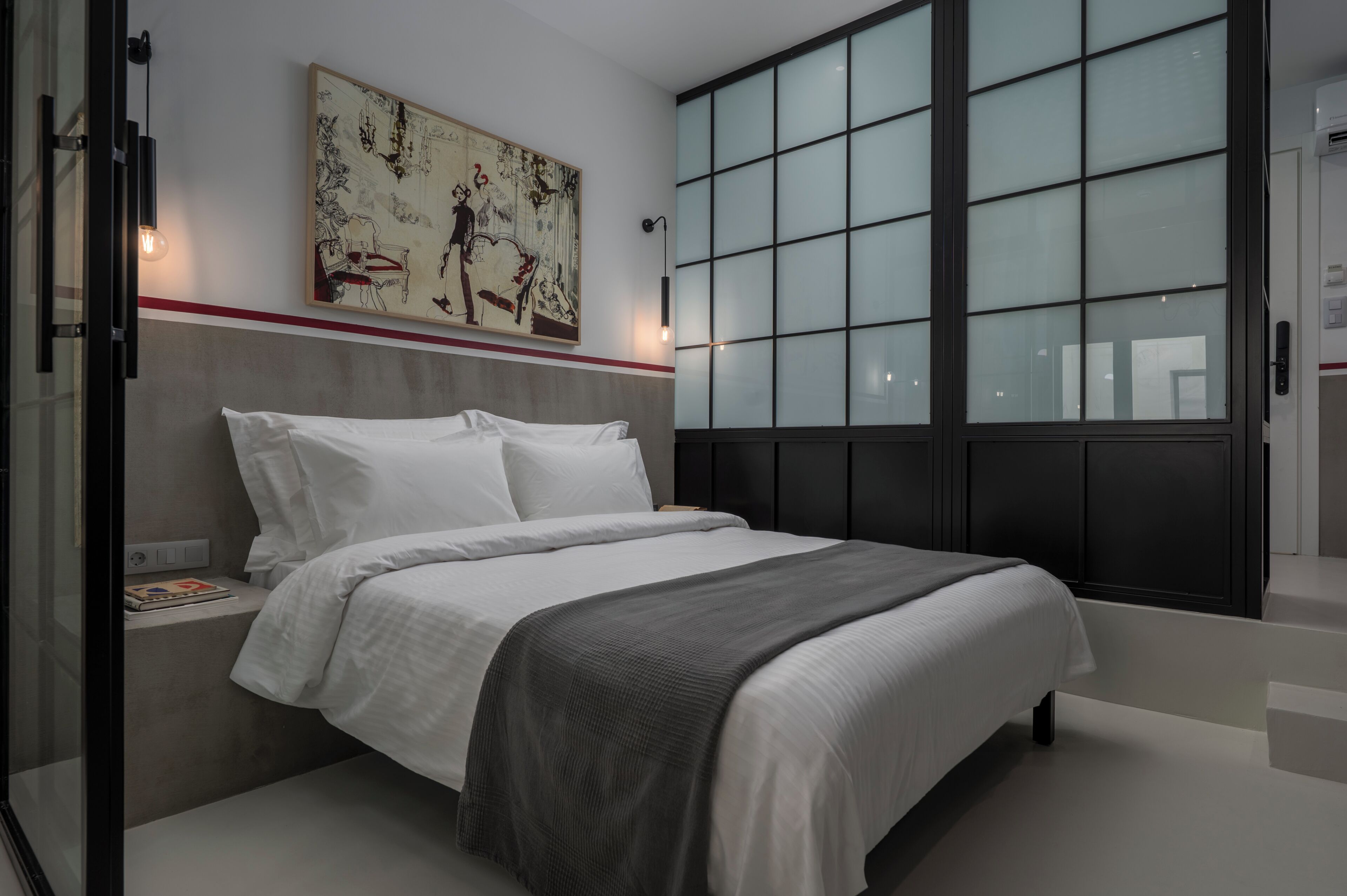 A modern bedroom with a large bed, a painting above it, and a large window with blinds.