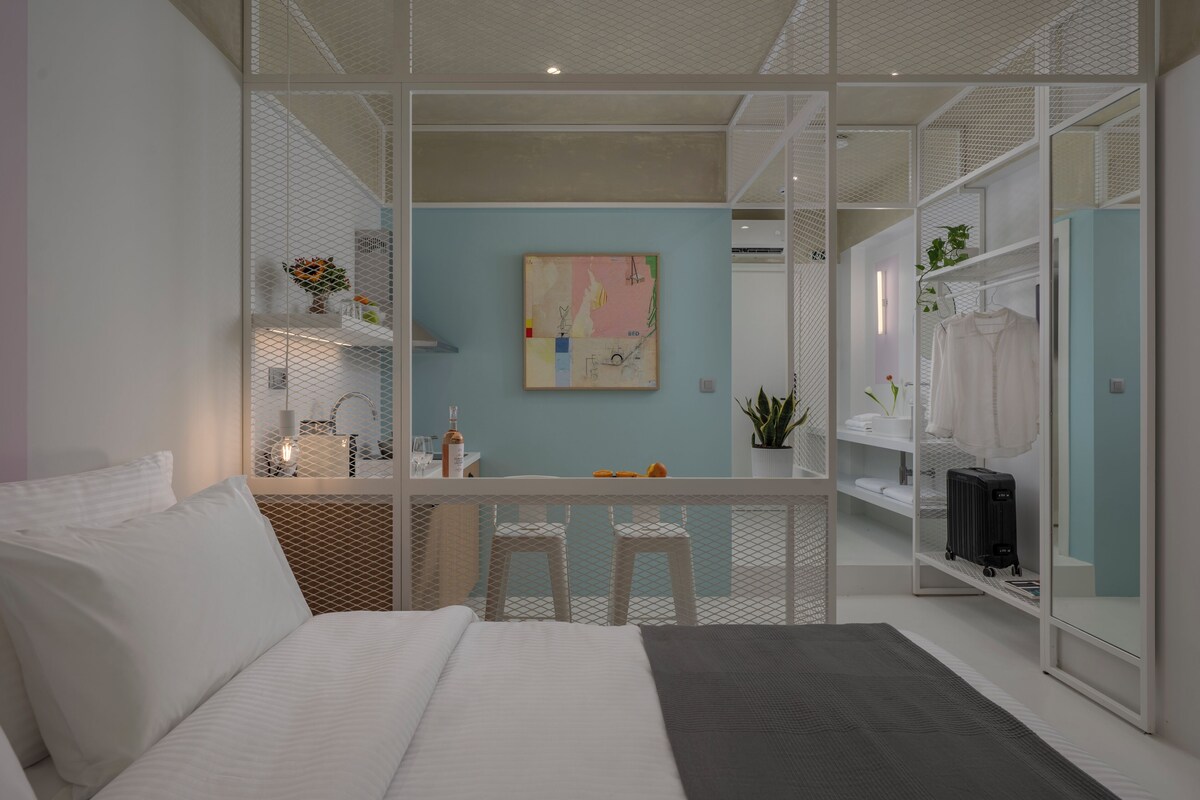A modern hotel room with a bed, a desk, and a seating area.
