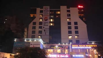 A hotel with a prominent sign for 'Hotel Maam Residency' and a banner advertising 'Vibes of India.'