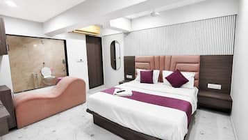 A modern hotel room with a large bed, a sitting area, and a bathroom.
