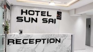 Uma receção de hotel com bancada de mármore e um letreiro vertical com a inscrição 'HOTEL SUN SAIP'.