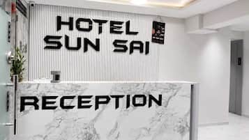 A hotel reception desk with a marble top and a vertical banner displaying 'HOTEL SUN SAIP'.