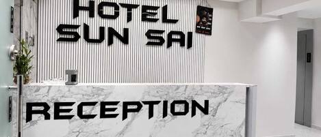 A hotel reception desk with a marble top and a vertical banner displaying 'HOTEL SUN SAIP'.