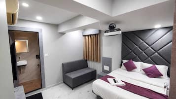 Une chambre d’hôtel moderne équipée d’un lit, d’un canapé, d’une salle de bain et d’un ventilateur de plafond.