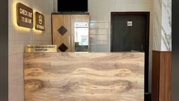 A reception desk with a marble-like surface, a red carpet, and a sign indicating check-out time.
