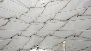 Casa de banho com parede de mármore branco, lavatório branco e sanita.