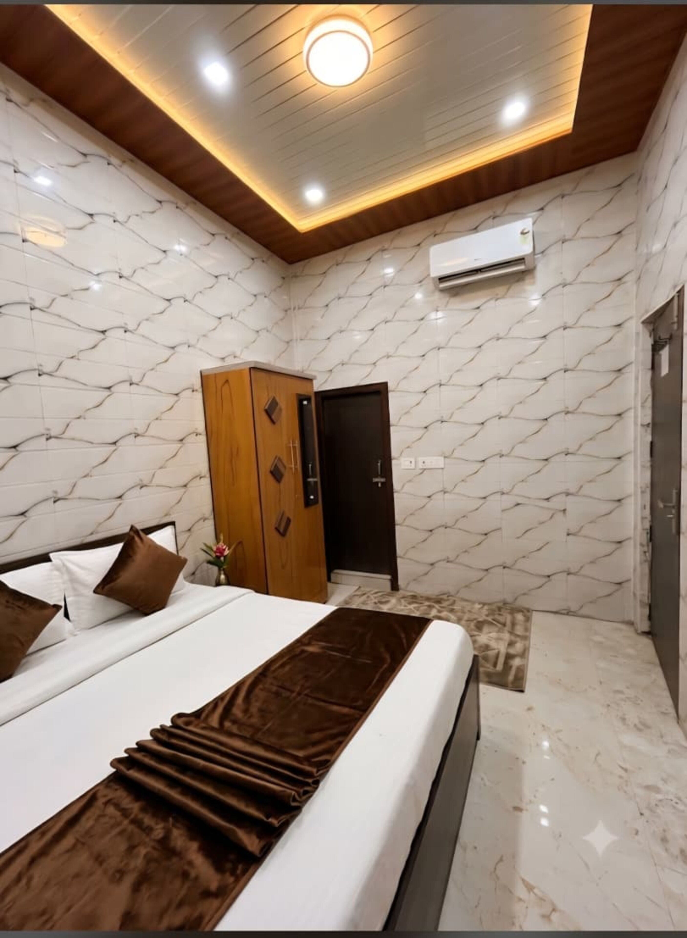 A modern bedroom with a bed, wooden wardrobe, and marble-patterned walls.