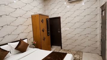 A modern bedroom with a bed, wooden wardrobe, and marble-patterned walls.