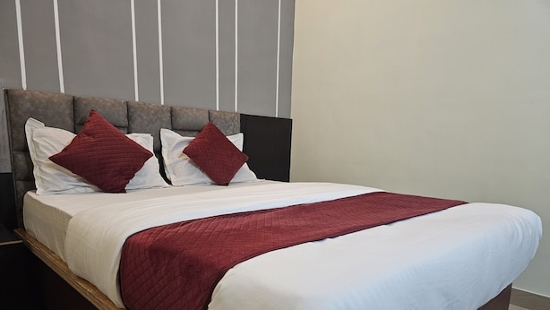 A bed with a wooden frame, white bedding, and red accents. - Sri Chaitanya Residency  (Mysore)