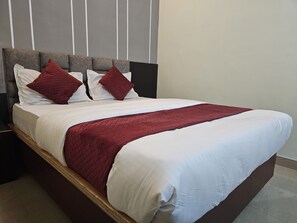 A bed with a wooden frame, white bedding, and red accents. - Sri Chaitanya Residency  (Mysore)