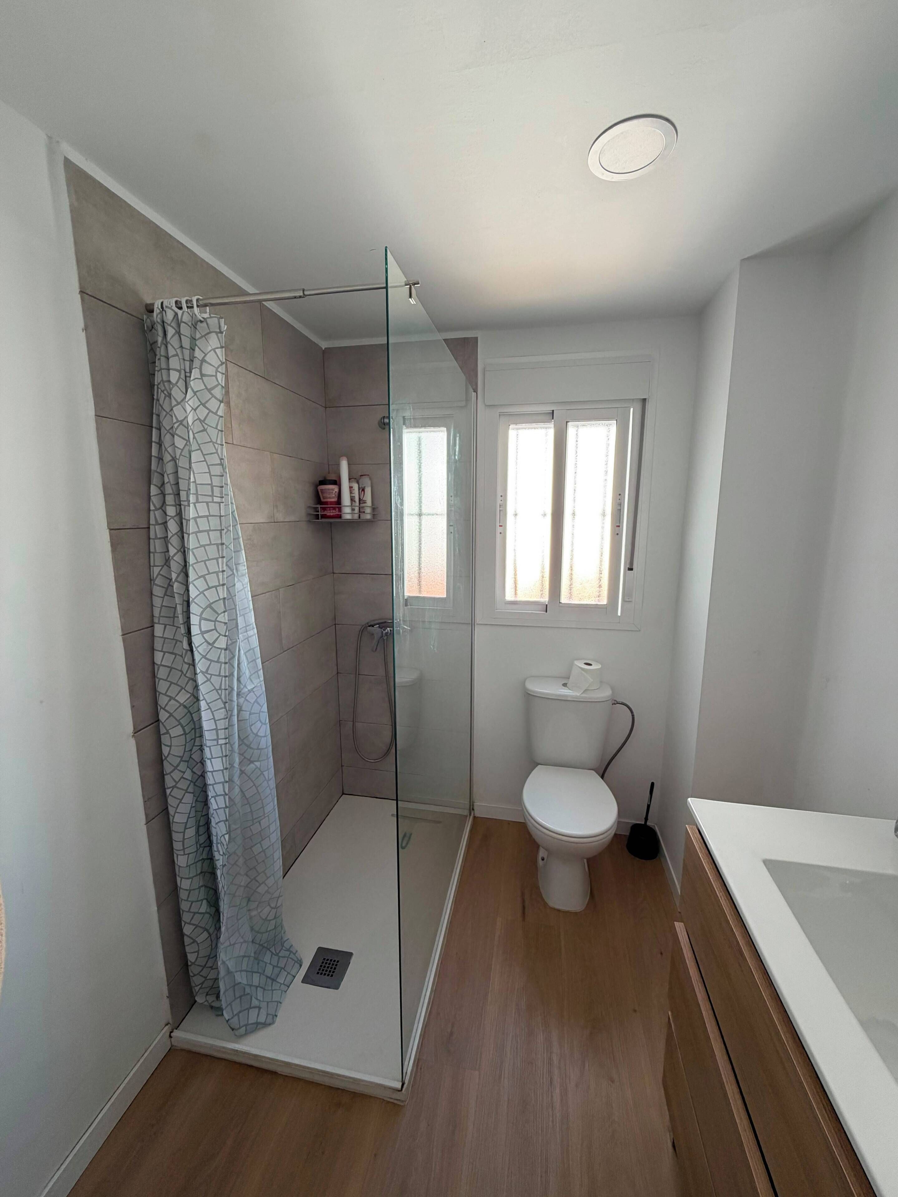 A modern bathroom with a glass-enclosed shower, a toilet, and a bathtub.