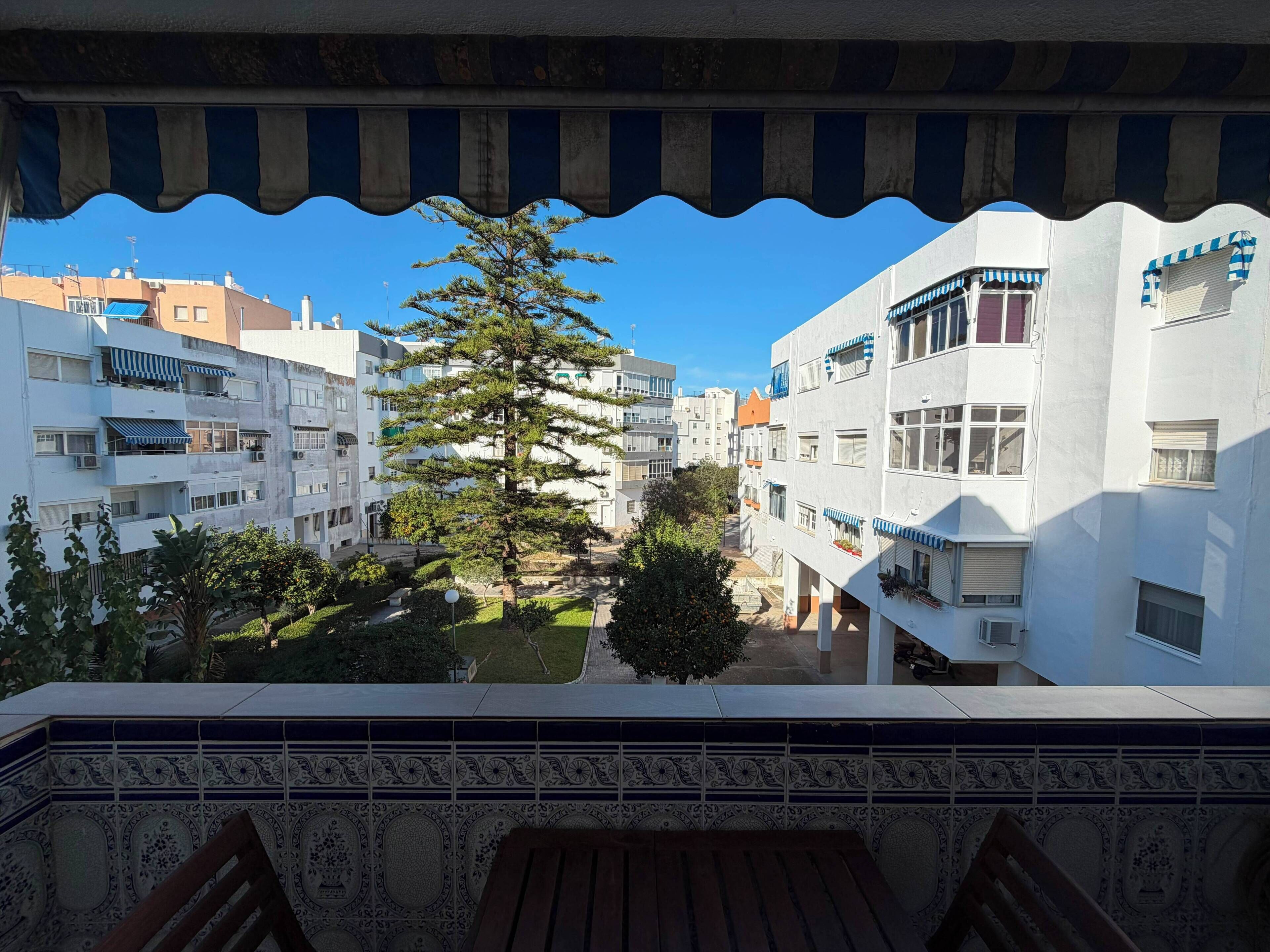 Ein Balkon mit Blick auf ein Wohngebiet, einschließlich Gebäude und eines Baumes.