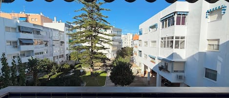 Un balcón con vistas a un área residencial, que incluye edificios y un árbol.