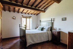 Une chambre à coucher avec un lit en bois, une table de chevet, une commode, une fenêtre avec des rideaux et un plafond en bois.
