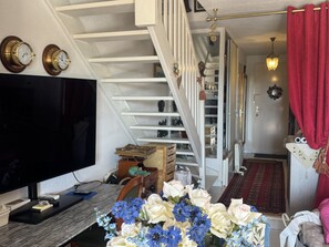 A living room with a flat-screen TV, a wooden coffee table, and a floral arrangement. - La Marianne with Sea View, Private Terrace, Air Conditioning (Fleury)