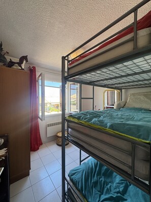 A bunk bed room with a window, a radiator, and a curtain. - La Marianne with Sea View, Private Terrace, Air Conditioning (Fleury)